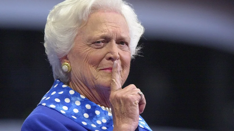 Att hon ber om tystnad är anledningen till att numera bortgångna presidenthustrun Barbara Bush är med på bild.