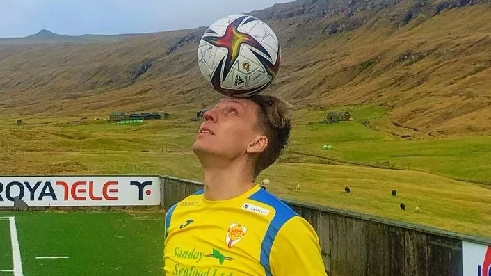 William Ankarhake vid klubbens anläggning som ligger vid vattnet omgiven av höga kullar. "Jag lyckades få med några av de 70000 får som finns på ön också" konstaterar han.