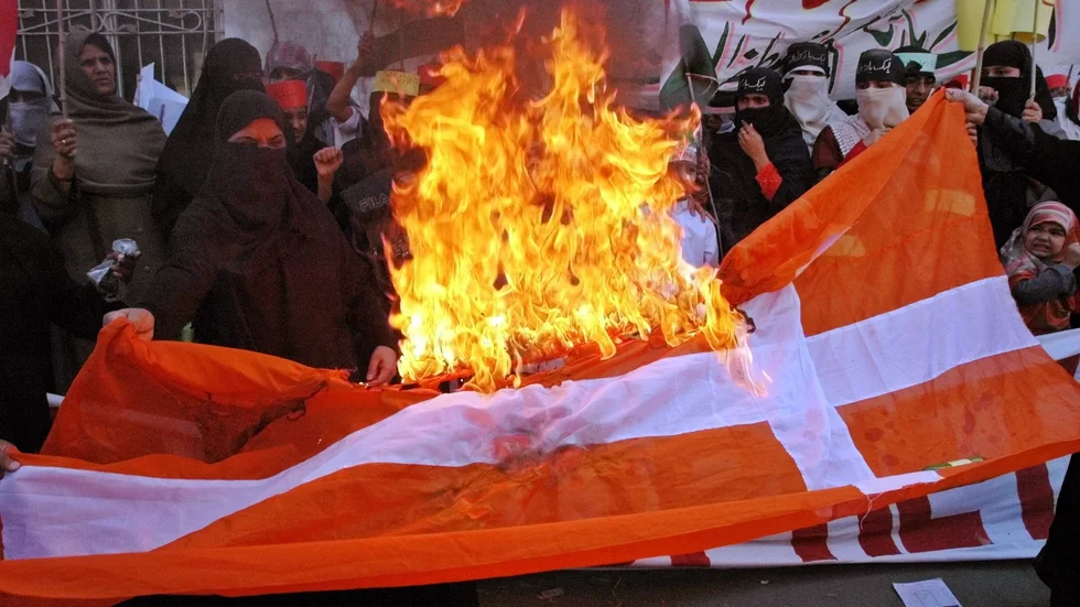Den danska flaggan antänds under en demonstration i Lahore i Pakistan den 24 februari 2006, i raseri mot Jyllands-Postens publicering av karikatyrer på profeten Muhammed. Arkivbild.