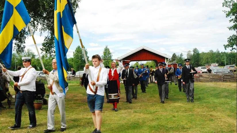 Rosenfors och Vena Musikkårer marscherar tillsammans med fanbärare från Venhagskolan till hembygdsparken.