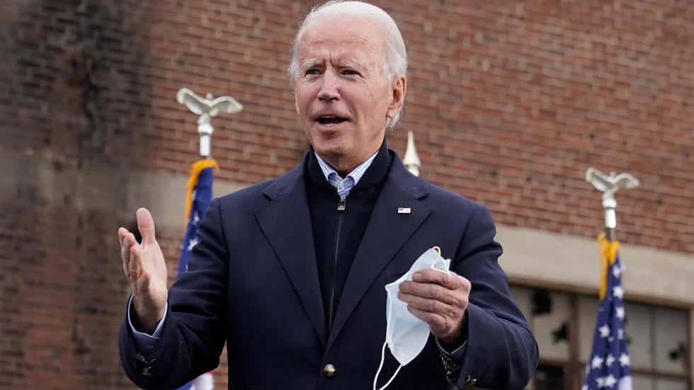 USA:s tillträdande president Joe Biden, med ett munskydd i handen, kommer att vaccineras mot covid-19 nästa vecka.