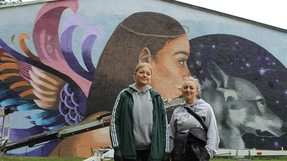 På torsdagen blev den klar, den stora målningen som täcker gaveln på Långbrottshallen. Frida Stiil Vium till höger har skapat motivet och fått hjälp att sprayfärga väggen av sin vän Anna Katrine Trads.