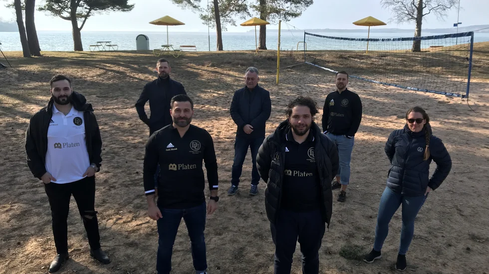Många vill vara med Dribbla Uniteds satsning på beach soccer intill Varamons och Vätterns turkosblå vatten. Vid sidan av Dribbla-ledarna ses representanter för kommun och RF-Sisu. Planen ska rustas upp.