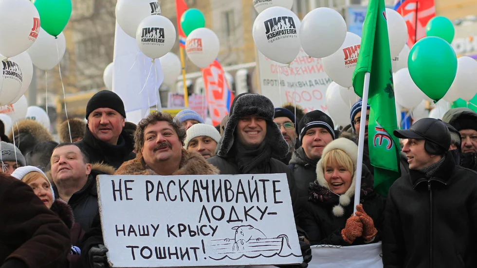 Författaren Dmitrij Bykov håller en skylt under en protest i Moskva 2012. Bredvid står oppositionsledaren Aleksej Navalnyj.