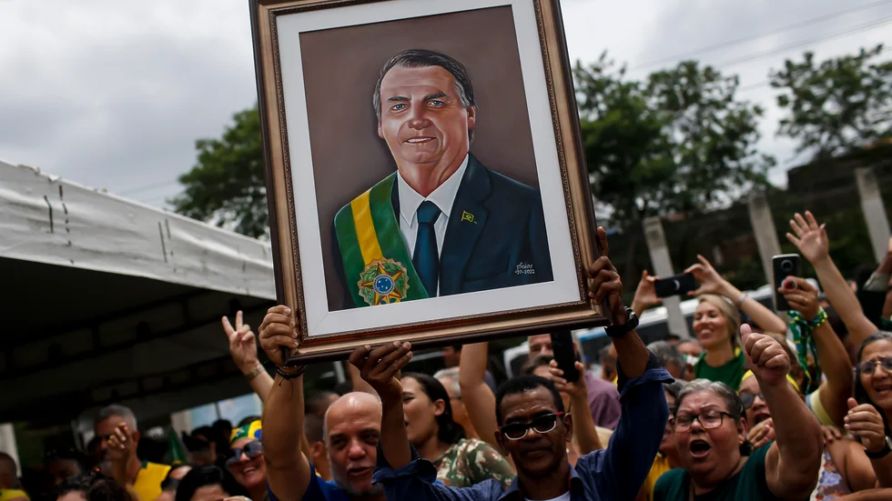 En anhängare till Jair Bolsonaro håller upp en tavla på presidenten vid ett valmöte i Rio de Janeiro. Fotot är taget 18 oktober.