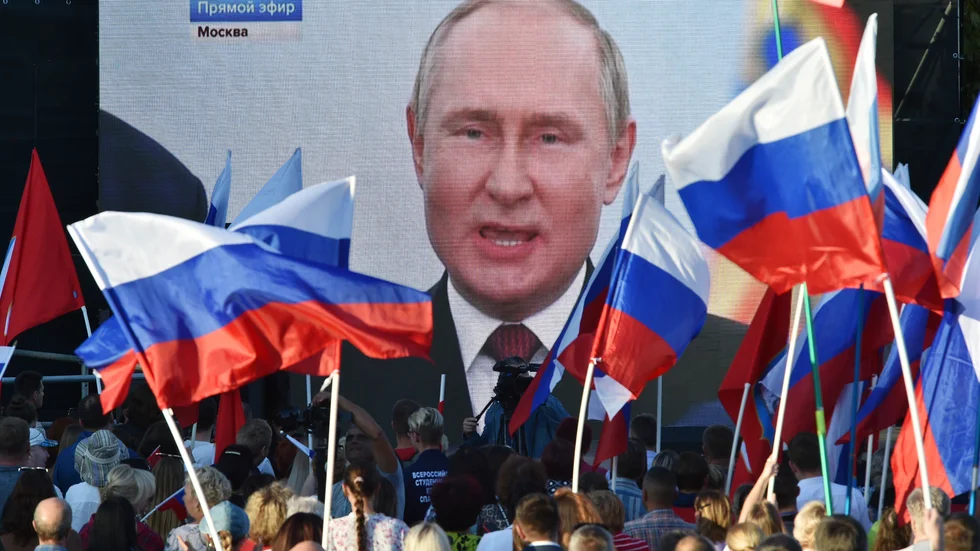 Människor ser på storbilds-tv president Vladimir Putin hålla tal inför annekteringen av fyra områden i Ukraina.