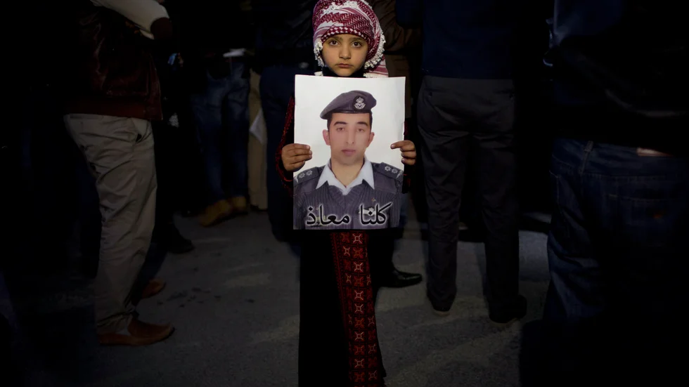 En flicka i Jordanien visar upp en bild på piloten Mu'adh al-Kasasibah som brändes till döds efter att ha tillfångatagits av terrorsekten IS i Syrien. Bilden togs under en sammankomst i Jordaniens huvudstad Amman i februari 2015.