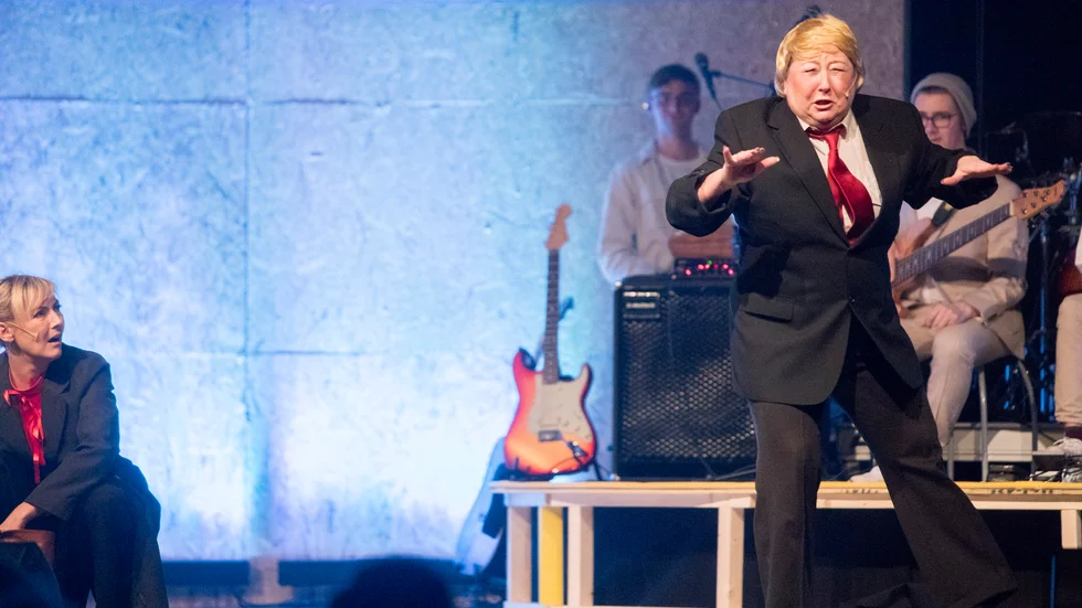 Lena Sirrewius som Donald Trump i "De folkvalda", Katrineholmsrevyn 2018. Det är till de folkvalda revygänget nu vänder sig för hjälp.