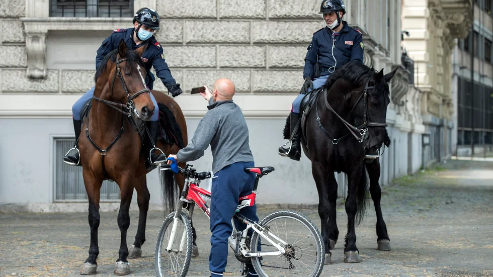 Poliser i Rom kontrollerar att en cyklist har rätt att vara ute och inte bryter mot restriktionerna för att minska smittspridningen.