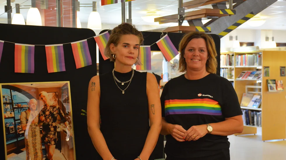 Zarah Ragnvaldsson (till vänster) är biblioteksassistent och har sett till att regnbågshyllorna nu finns på plats på biblioteket. De invigdes under torsdagen av Eva Kindstrand (till höger), ordförande i Storebro IF och förtroendevald i IF Metall. 