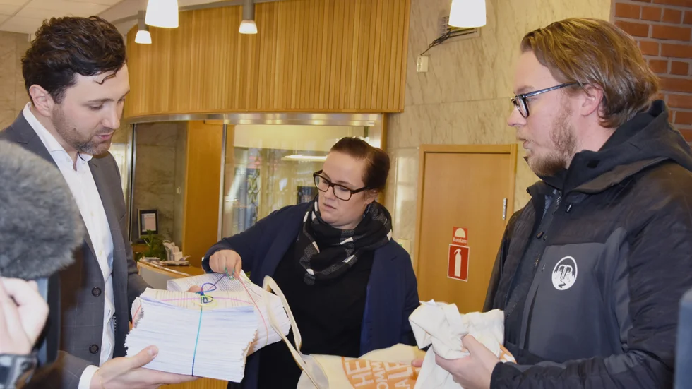 Pontus Johansson, ordförande för folkinitiativet "Hela kommunen ska leva och lära", lämnar över luntan med namnunderskrifter till Nahid Zara, ordförande i kommunfullmäktiges presidium.
