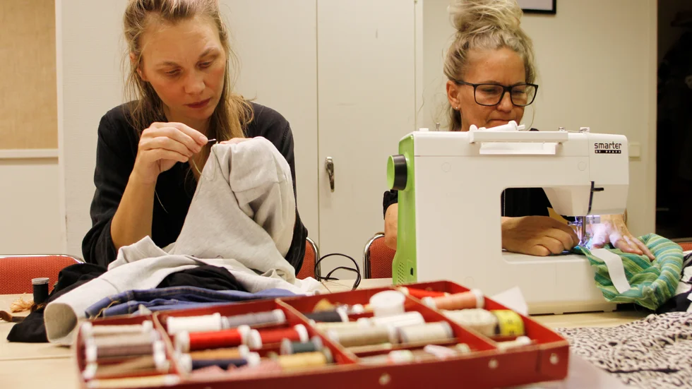 Lina Östling och Therese Pettersson arbetar med sina projekt; att laga ett hål med en synlig söm och att göra om en klänning till en kjol.